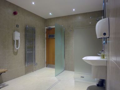 A bathroom with a shower area sink hand dryer and towel rack at 23 Burgh Island Causeway in Bigbury-on-Sea