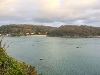 A view of a bay with boats on water and houses on a hillside at Orchard View in Kellaton near Hallsands