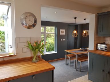 A kitchen with wooden countertops and a dining area with a wooden table and benches at Orchard View in Kellaton near Hallsands
