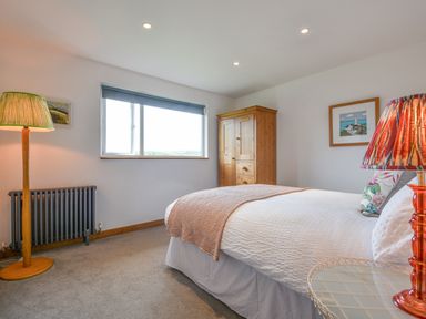 A bedroom with a bed a wooden wardrobe two lamps and a window at Orchard View in Kellaton near Hallsands