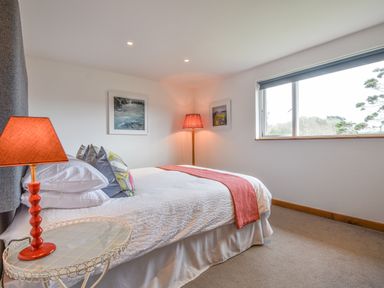 A bedroom with a bed a red lamp on a side table and a window at Orchard View in Kellaton near Hallsands