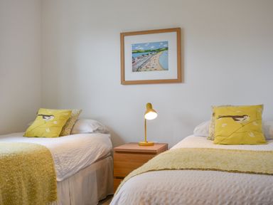 A bedroom with two single beds a wooden nightstand and a framed picture on the wall at Orchard View in Kellaton near Hallsands