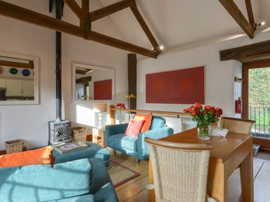 A living room with blue sofas and a wooden dining table with flowers at Mixit Cottage in Kingsbridge