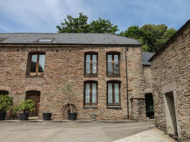 An outdoor area with stone walls and windows at Mixit Cottage in Kingsbridge