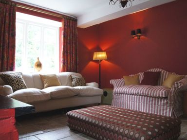 A sitting room with a white sofa and striped armchair with cushions a floor lamp and polka dot ottoman at Maristow Barton in Milton Combe near Lopwell Dam