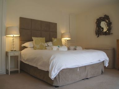 A bedroom with a large bed bedside tables with lamps and a decorative mirror at Maristow Barton Milton Combe near Lopwell Dam