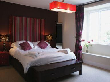 A bedroom with a large bed with striped headboard and bedside tables with lamps at Maristow Barton in Milton Combe near Lopwell Dam