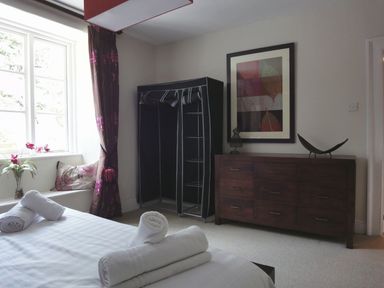 A bedroom with a bed with rolled towels a window with floral curtains a dresser with framed artwork and a fabric wardrobe at Maristow Barton in Milton Combe near Lopwell Dam