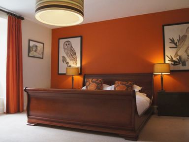 A bedroom with a wooden sleigh bed flanked by two table lamps under bird artwork at Maristow Barton in Milton Combe near Lopwell Dam