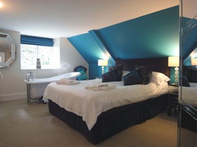 A bedroom with a bed a freestanding bathtub and lamps at Maristow Barton in Milton Combe near Lopwell Dam