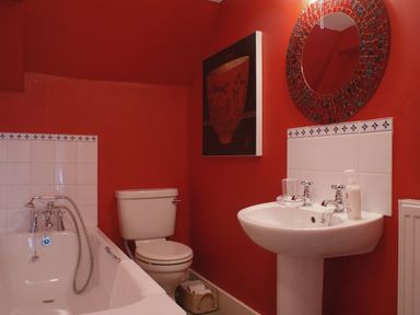 A bathroom with a bathtub toilet and pedestal sink a round mirror and wall art at Maristow Barton in Milton Combe near Lopwell Dam