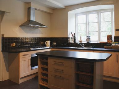 A kitchen with a stove oven island and window at Maristow Barton in Milton Combe near Lopwell Dam