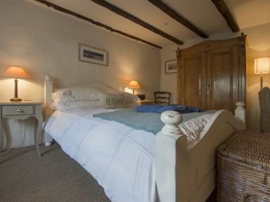 A bedroom with a bed a wooden wardrobe bedside tables and lamps at Cherry Tree Cottage in Noss Mayo