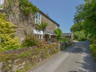 A stone cottage with plants and flowers along a narrow road at 1 Gabberwell Cottages in Kingston