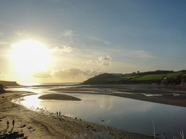 A beach with water channels and people walking near the shoreline at 1 Gabberwell Cottages in Kingston