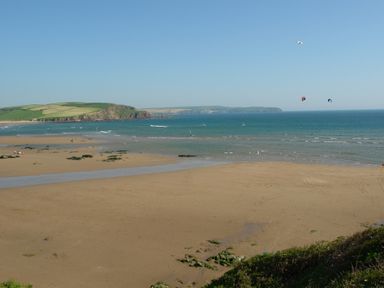 A beach with sand and small rocks with the ocean and green hills in the background at 1 Gabberwell Cottages in Kingston