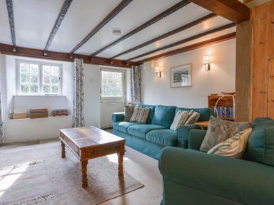 A living room with blue sofas a wooden coffee table and beams on the ceiling at 1 Gabberwell Cottages Kingston