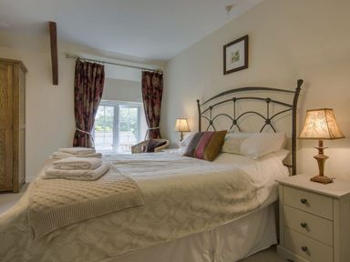 A bedroom with a double bed chairs side tables lamps and a wardrobe at Yellowland Farm in Holsworthy