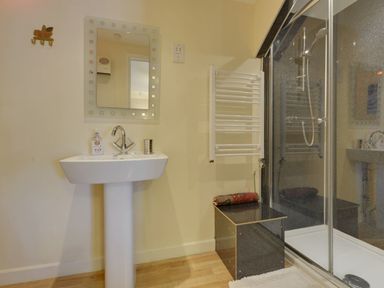 A bathroom with a pedestal sink mirror shower enclosure and towel rack at Yellowland Farm in Holsworthy