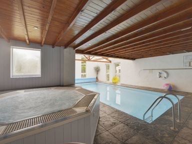 An indoor swimming pool and hot tub with wooden ceiling and tiled floor at Yellowland Farm in Holsworthy