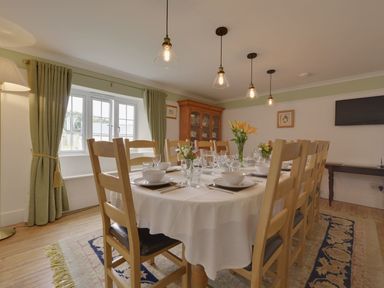 A dining room with a table set for a meal and wooden chairs at Yellowland Farm in Holsworthy