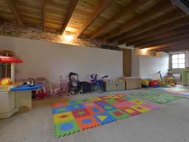 A playroom with colorful foam mats toys strollers and a window at Yellowland Farm in Holsworthy