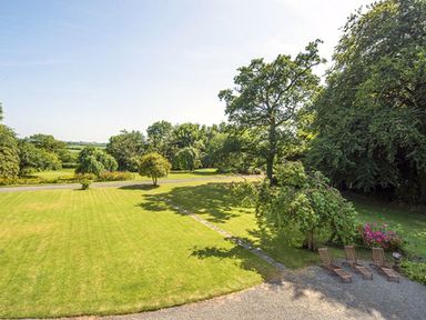 A garden with trimmed grass trees and four wooden sun loungers at Parnacott in Holsworthy