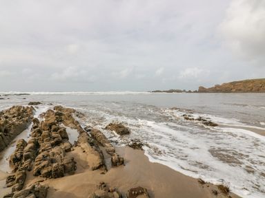 A beach with rock formations and waves at Parnacott in Holsworthy