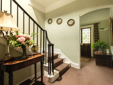 A hallway with a staircase and flower arrangement at Parnacott in Holsworthy