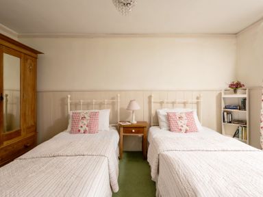 A bedroom with two beds and a wardrobe at Parnacott in Holsworthy