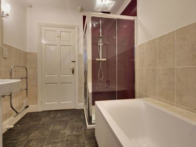 A bathroom with a bathtub shower enclosure sink and white door at Higher Tumrose in Blisland