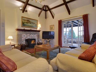 A living room with sofas a fireplace and a television at Higher Tumrose in Blisland
