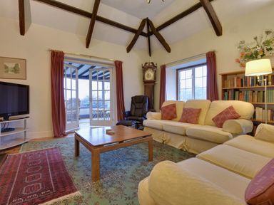 A living room with sofas pillows a wooden coffee table grandfather clock and a television at Higher Tumrose in Blisland