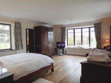 A bedroom with a bed wardrobe television towels and large windows at Higher Tumrose in Blisland