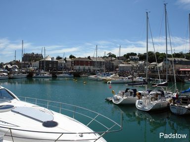 A harbor with boats and yachts docked near buildings in Padstow