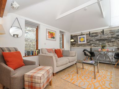 A living room with sofas armchair glass coffee table and a dining table with chairs at Swallow Barn in St Kew