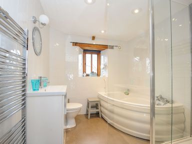 A bathroom with a bathtub shower toilet sink and a wooden stool at Swallow Barn in St Kew