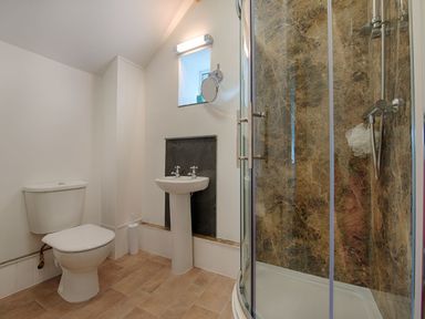 A bathroom with a toilet sink and a shower with marble walls at Salty Cottage in Morwenstow