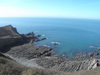 A rocky coastal shoreline with cliffs and ocean at Salty Cottage in Morwenstow