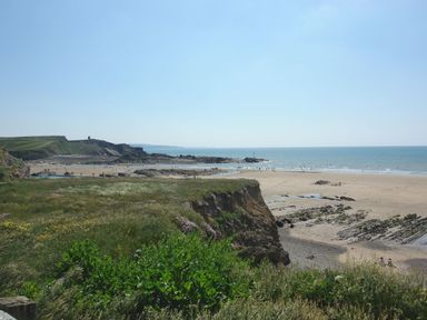A coastal landscape with cliffs grassy areas and a sandy beach by the sea at The Loft in Bude