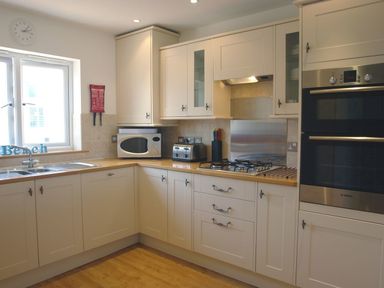 A kitchen with white cabinets a microwave toaster gas stove and built in oven at The Loft in Bude