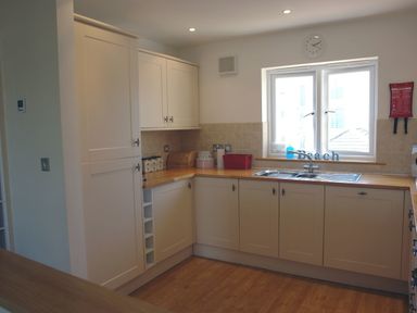A kitchen with white cabinets wooden countertops a double sink and a window at The Loft in Bude