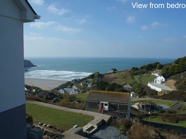 View of houses on a hillside overlooking a beach and ocean at Seagulls Perch in Mawgan Porth