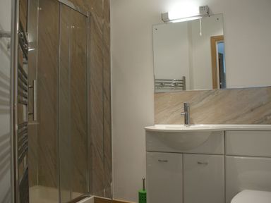 A bathroom with a shower cubicle a sink with cabinet and a mirror at Seagulls Perch in Mawgan Porth