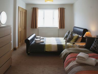 A bedroom with two beds a chest of drawers a lamp and folded towels at Seagulls Perch in Mawgan Porth