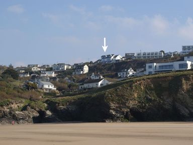 A coastal hillside with houses above a sandy beach at Seagulls Perch in Mawgan Porth