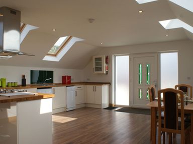 A kitchen with wooden countertops dining table and skylights at Seagulls Perch in Mawgan Porth