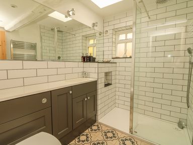 A bathroom with a shower enclosure a sink with cabinet and a tiled floor at Cousham Cottage in Kingsand And Cawsand