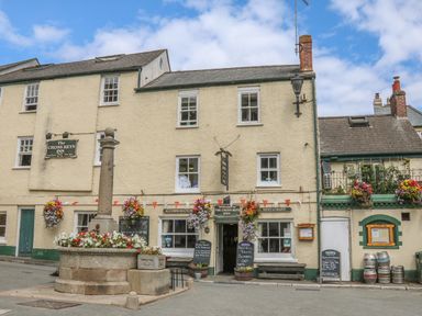 Exterior view of The Cross Keys Inn with hanging flower baskets a stone monument and beer kegs outside Cousham Cottage Kingsand And Cawsand