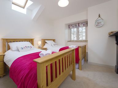 A bedroom with two single wooden beds with white bedding and red blankets at Nirvana in Kingsand And Cawsand